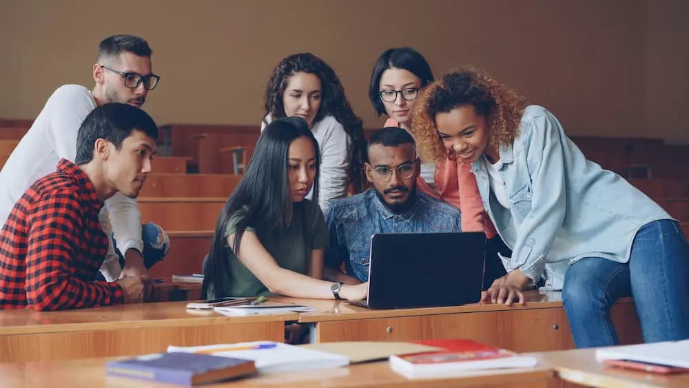 Groupe d'étudiants collaborant autour d'un ordinateur portable dans une salle de classe