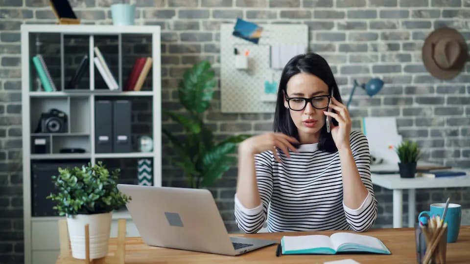 Femme professionnelle avec lunettes utilisant son téléphone au bureau